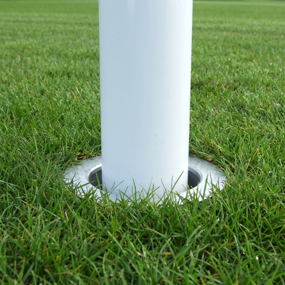 White aluminium rugby post upright dropped into a ground socket set level with the turf