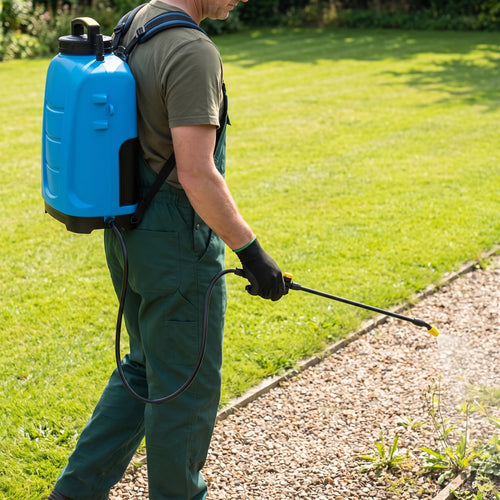 Gardener using the 15L battery electric knapsack sprayer with a single lance to spray weeds along a garden gravel path