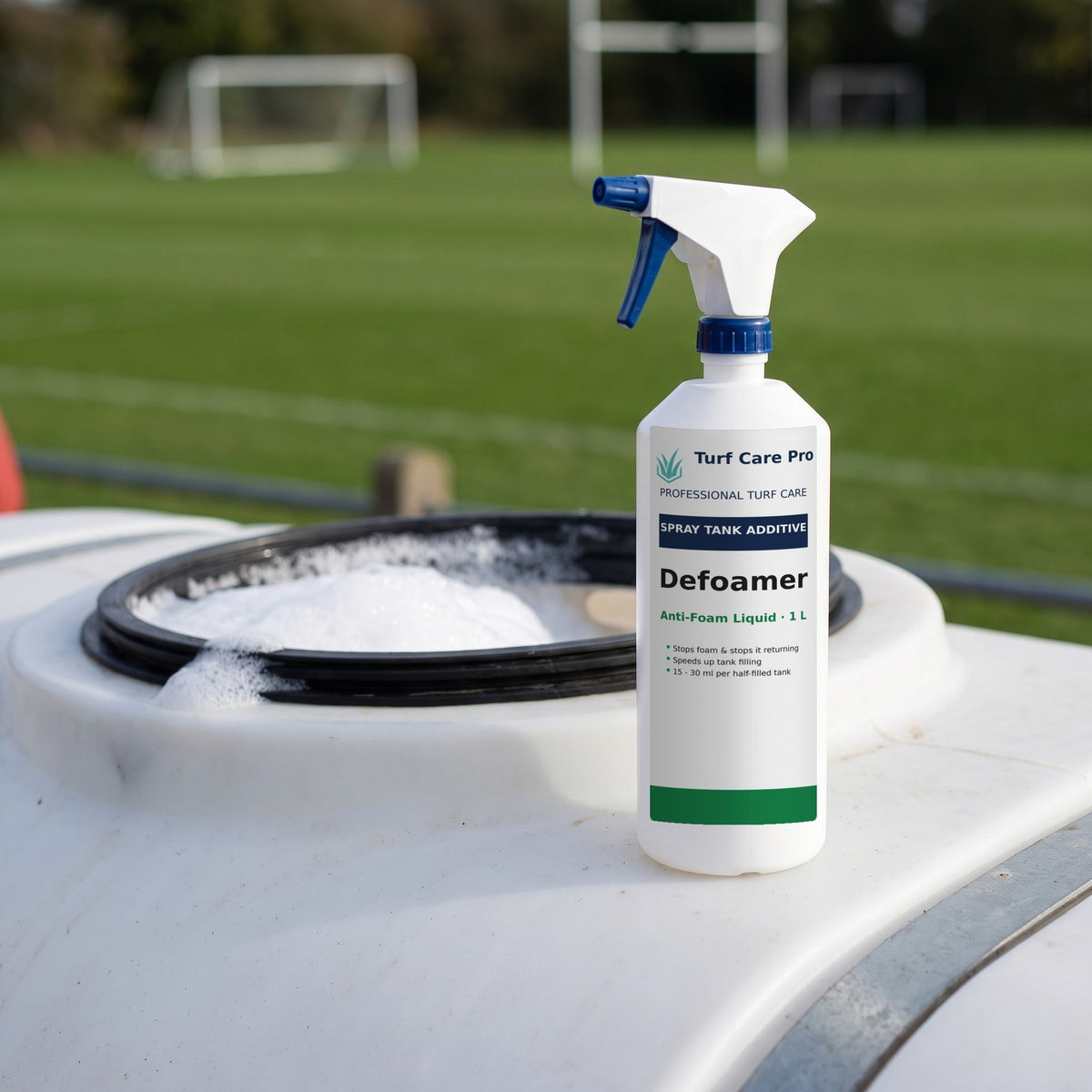 1L anti-foam defoamer bottle on a sprayer tank beside a foaming fill hatch at a sports pitch