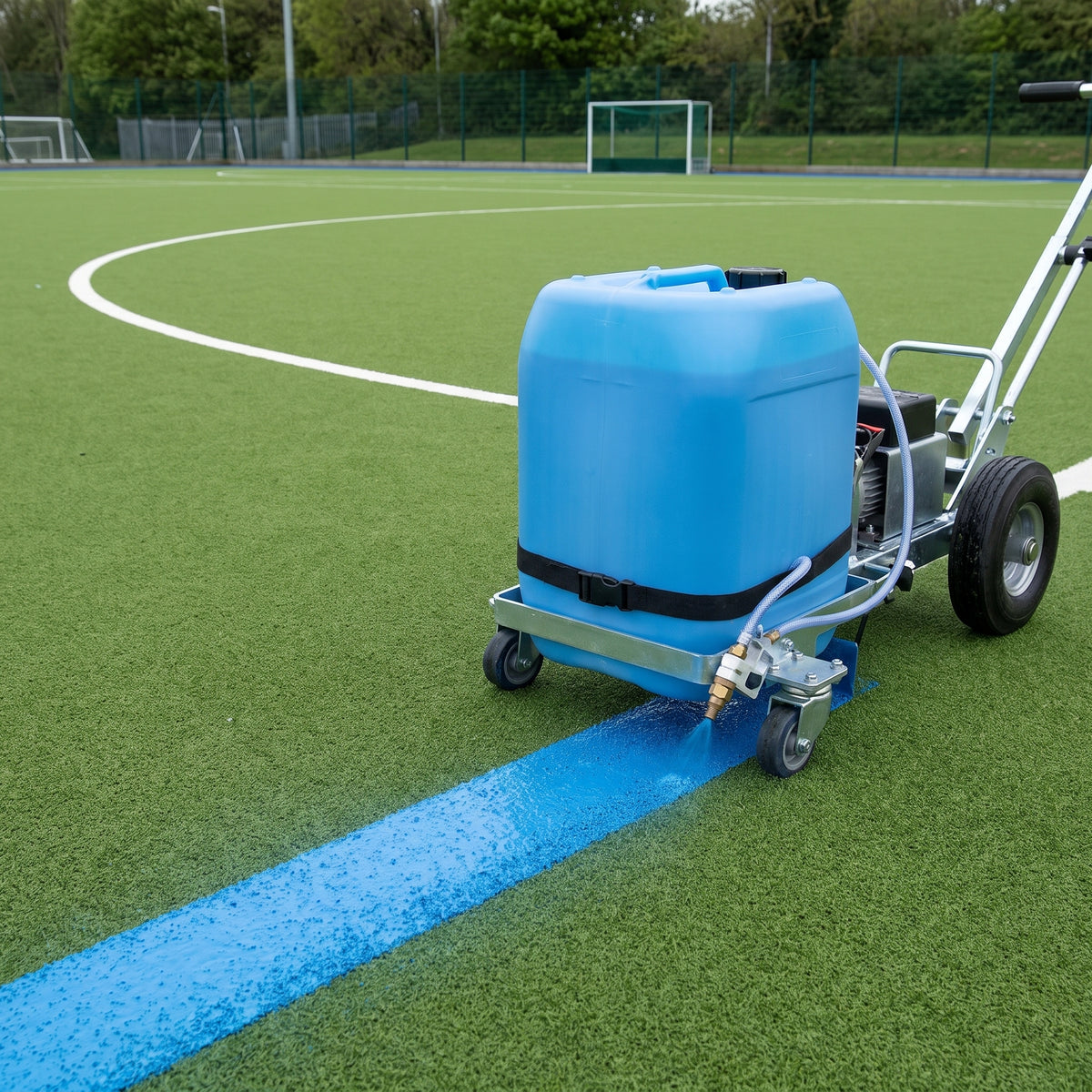 Blue water-based line marking paint applied by spray marker on a synthetic hockey pitch