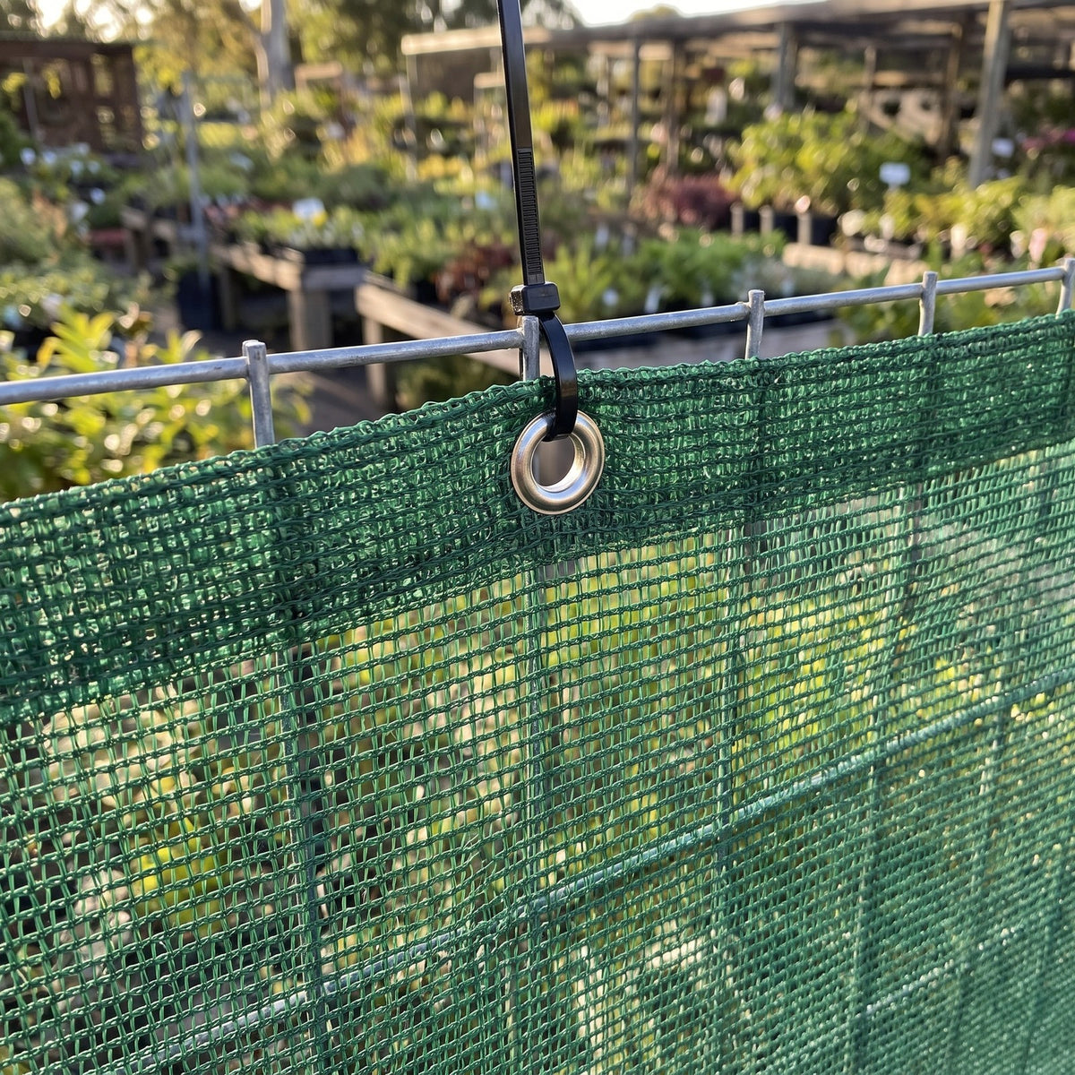 Close-up of knitted monofilament windbreak netting showing an eyelet tied to a wire